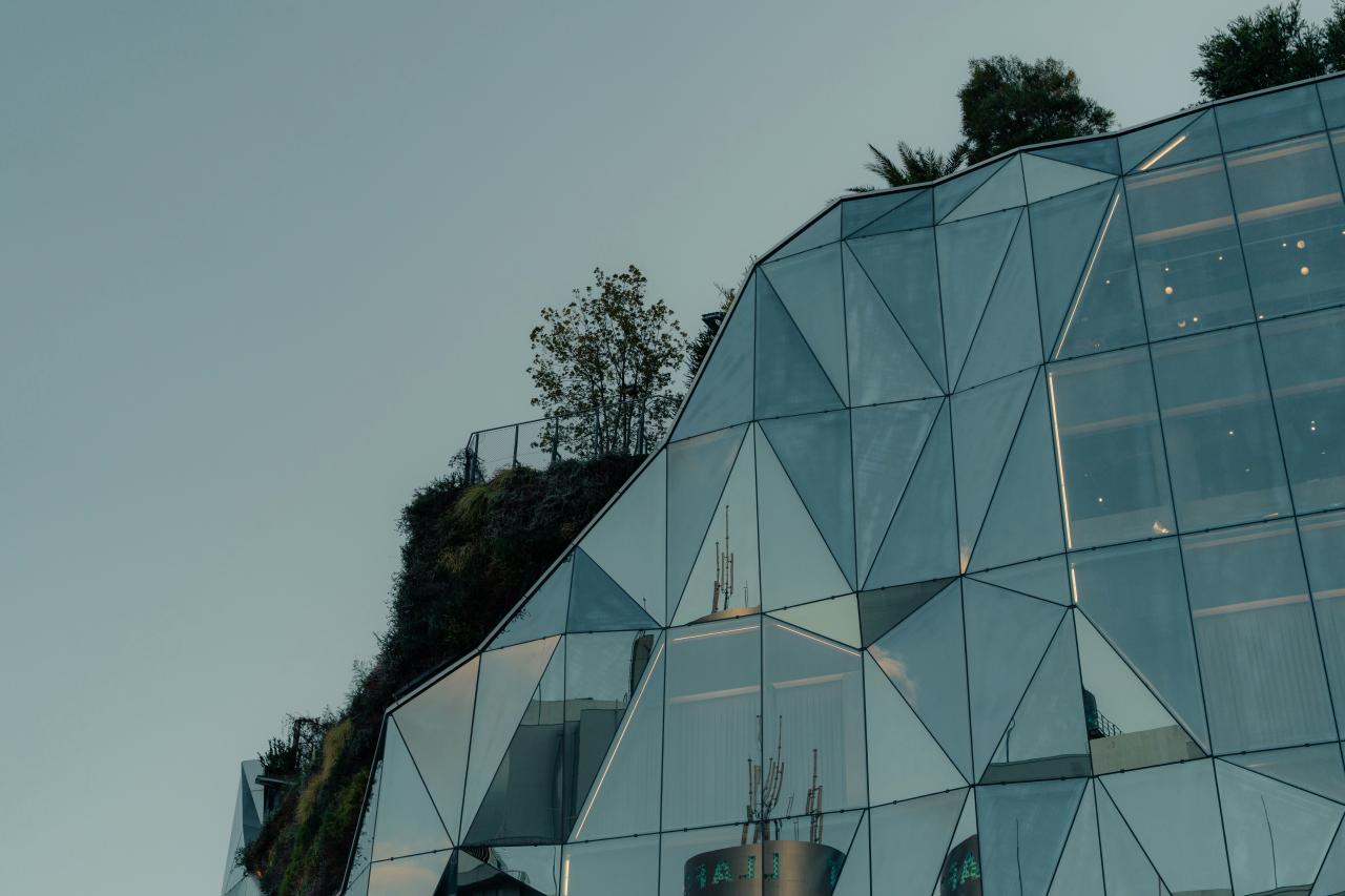 Modern building with geometric glass facade and rooftop greenery